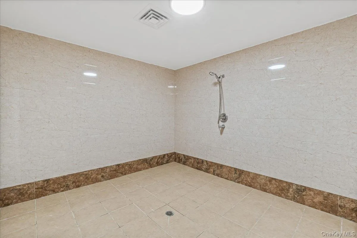 Bathroom featuring tiled shower and tile patterned flooring Bathroom featuring tiled shower and tile patterned flooring