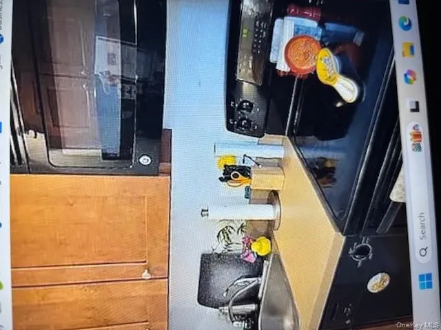 Kitchen featuring black microwave, range, light countertops, decorative backsplash, and brown cabinets Kitchen featuring black microwave, range, light countertops, decorative backsplash, and brown cabinets