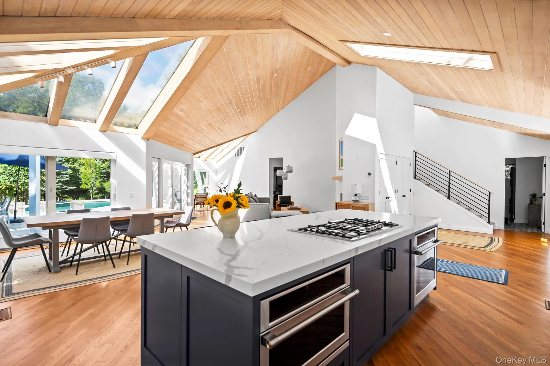 Kitchen featuring cabinetry, a skylight, wood finished floors, appliances with stainless steel finishes, and light stone counters Kitchen featuring cabinetry, a skylight, wood finished floors, appliances with stainless steel finishes, and light stone counters