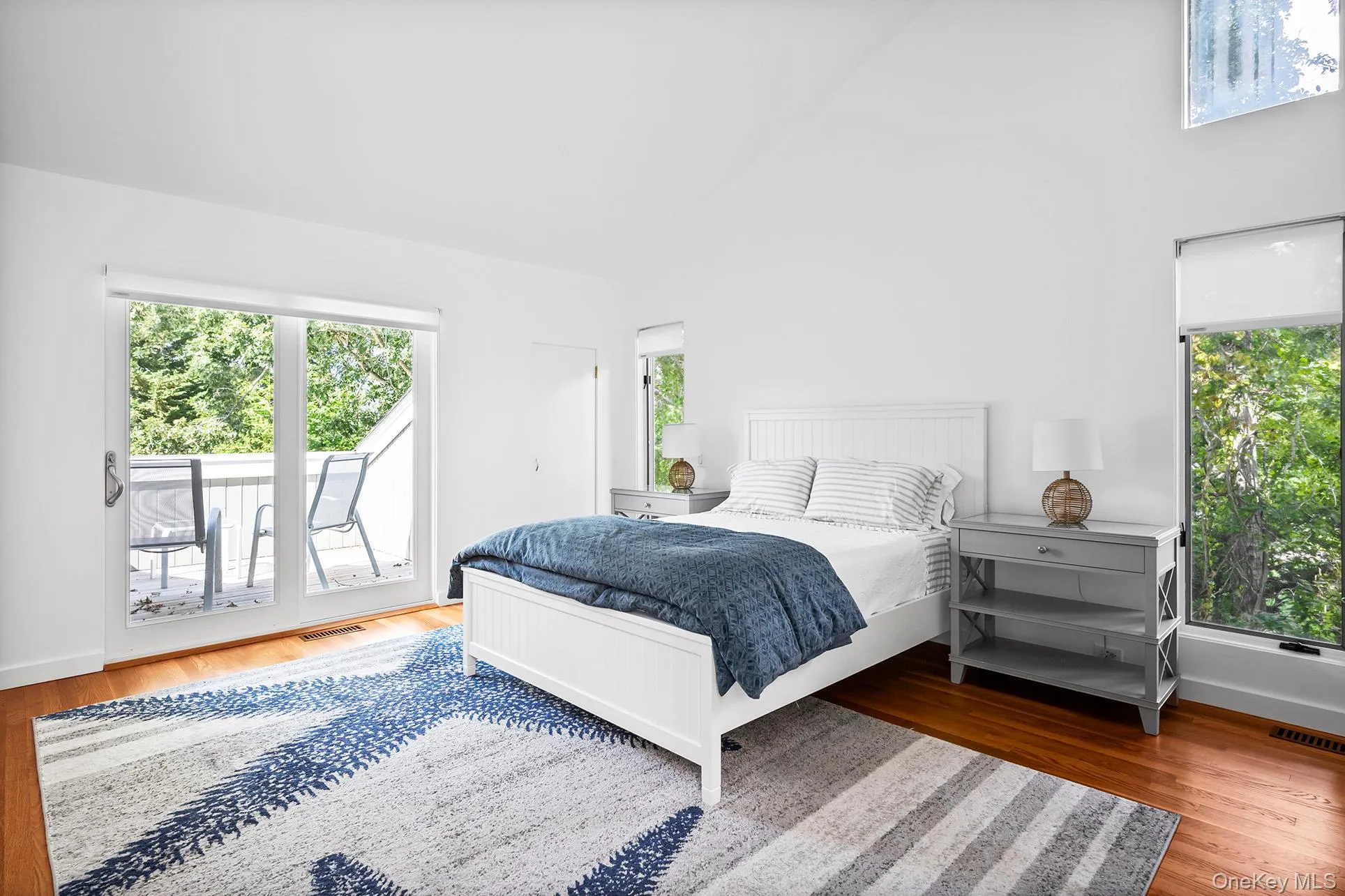 Bedroom with multiple windows, high vaulted ceiling, wood finished floors, and access to outside Bedroom with multiple windows, high vaulted ceiling, wood finished floors, and access to outside