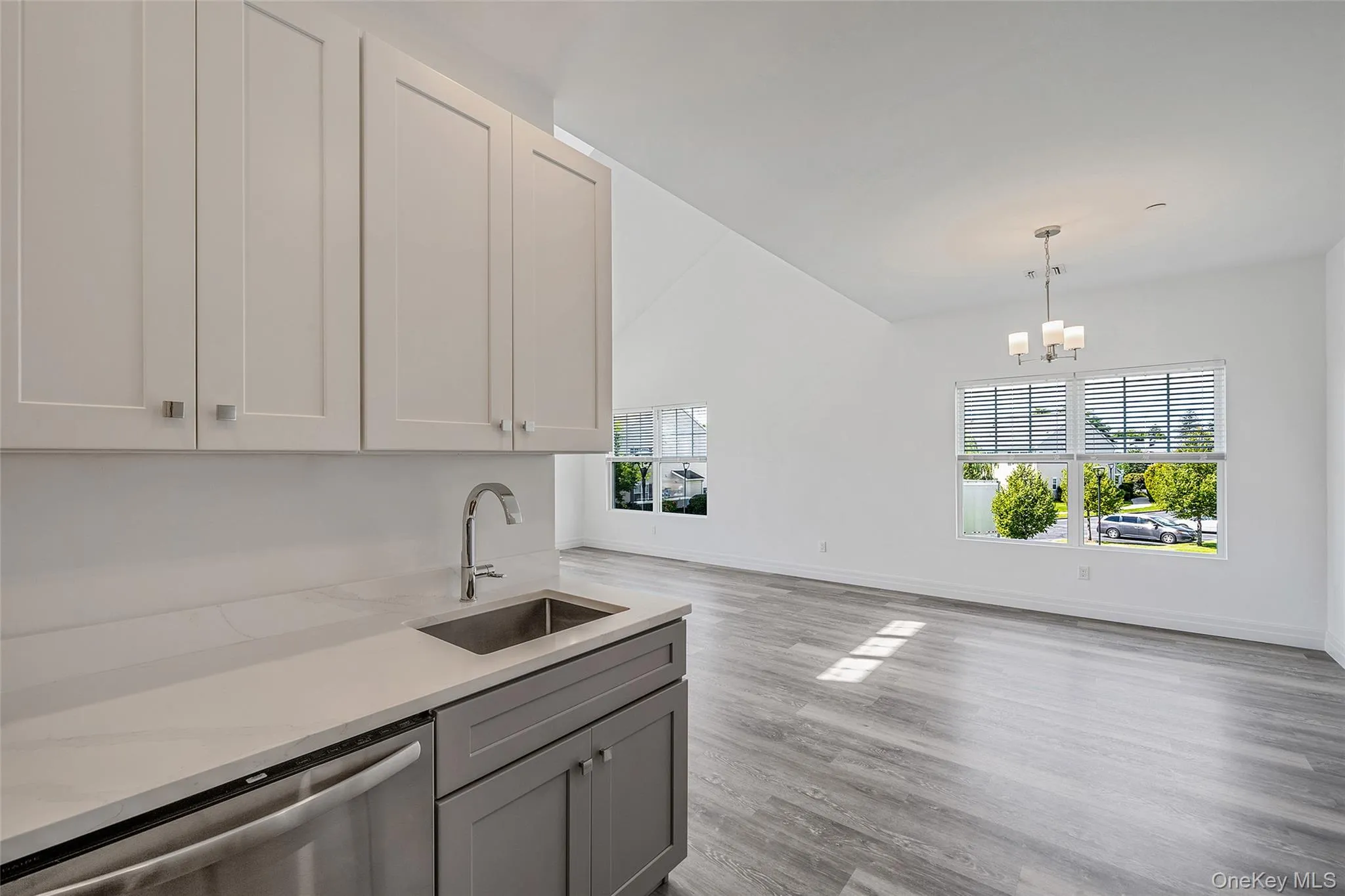Kitchen with dishwasher, light wood finished floors, light stone counters, decorative light fixtures, and a chandelier Kitchen with dishwasher, light wood finished floors, light stone counters, decorative light fixtures, and a chandelier