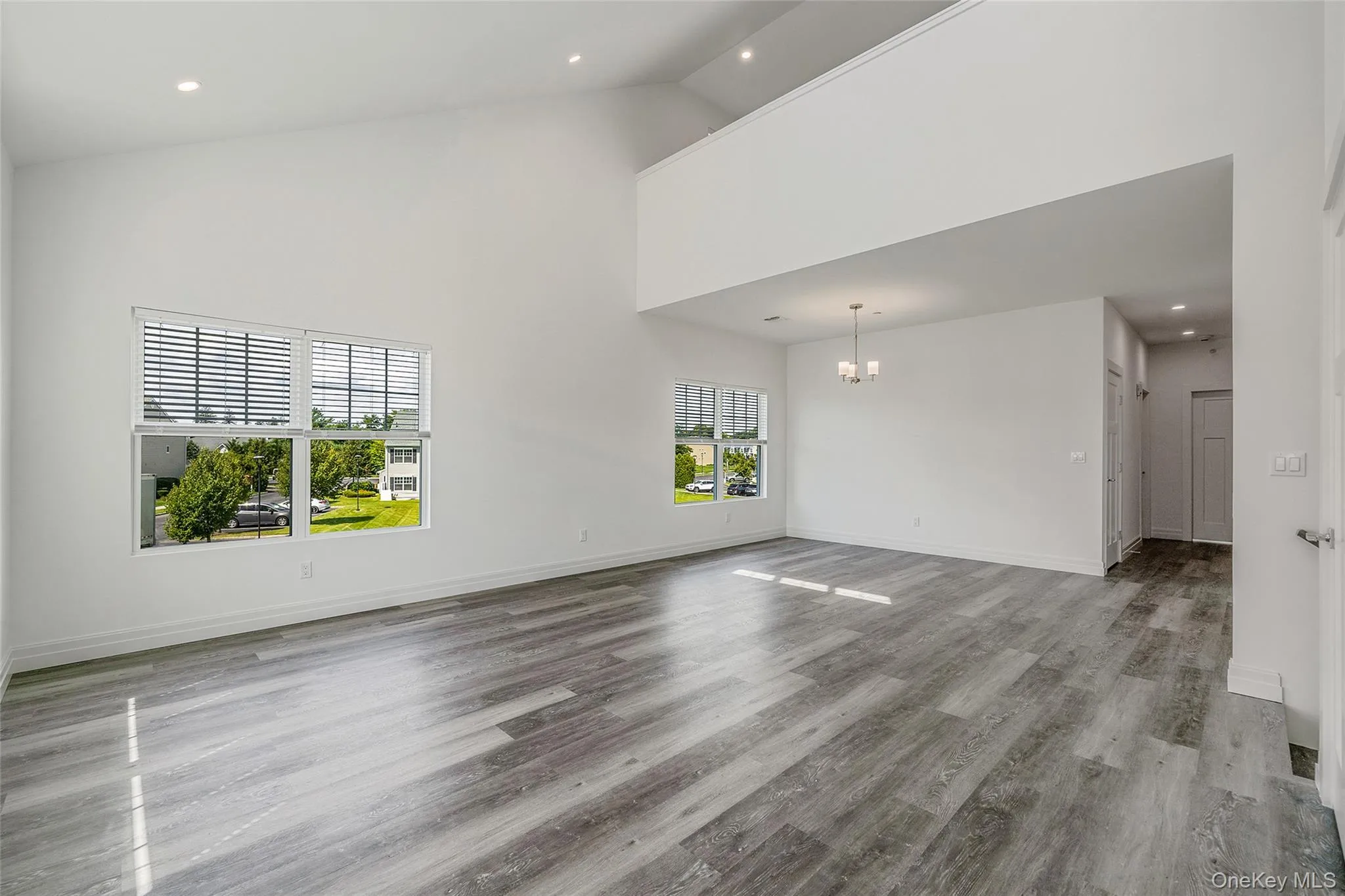 Unfurnished living room featuring high vaulted ceiling, recessed lighting, light wood-style flooring, and a chandelier Unfurnished living room featuring high vaulted ceiling, recessed lighting, light wood-style flooring, and a chandelier