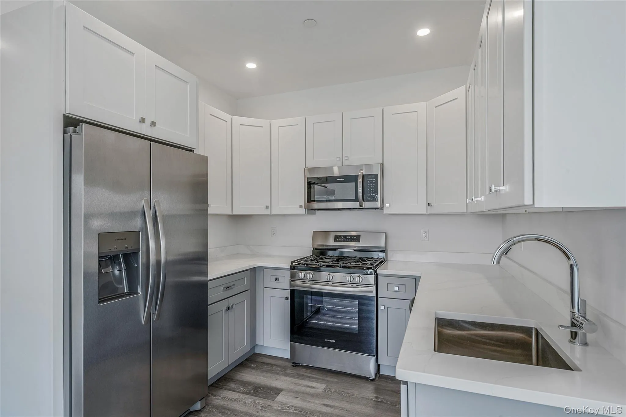 Kitchen with stainless steel appliances, light stone counters, light wood-type flooring, white cabinets, and recessed lighting Kitchen with stainless steel appliances, light stone counters, light wood-type flooring, white cabinets, and recessed lighting