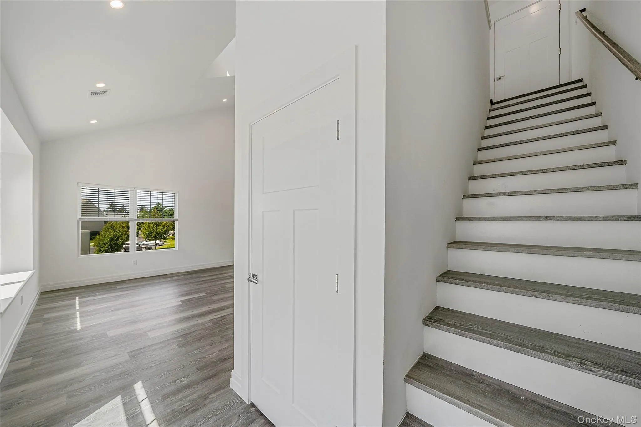 Stairs with recessed lighting, high vaulted ceiling, and wood finished floors Stairs with recessed lighting, high vaulted ceiling, and wood finished floors