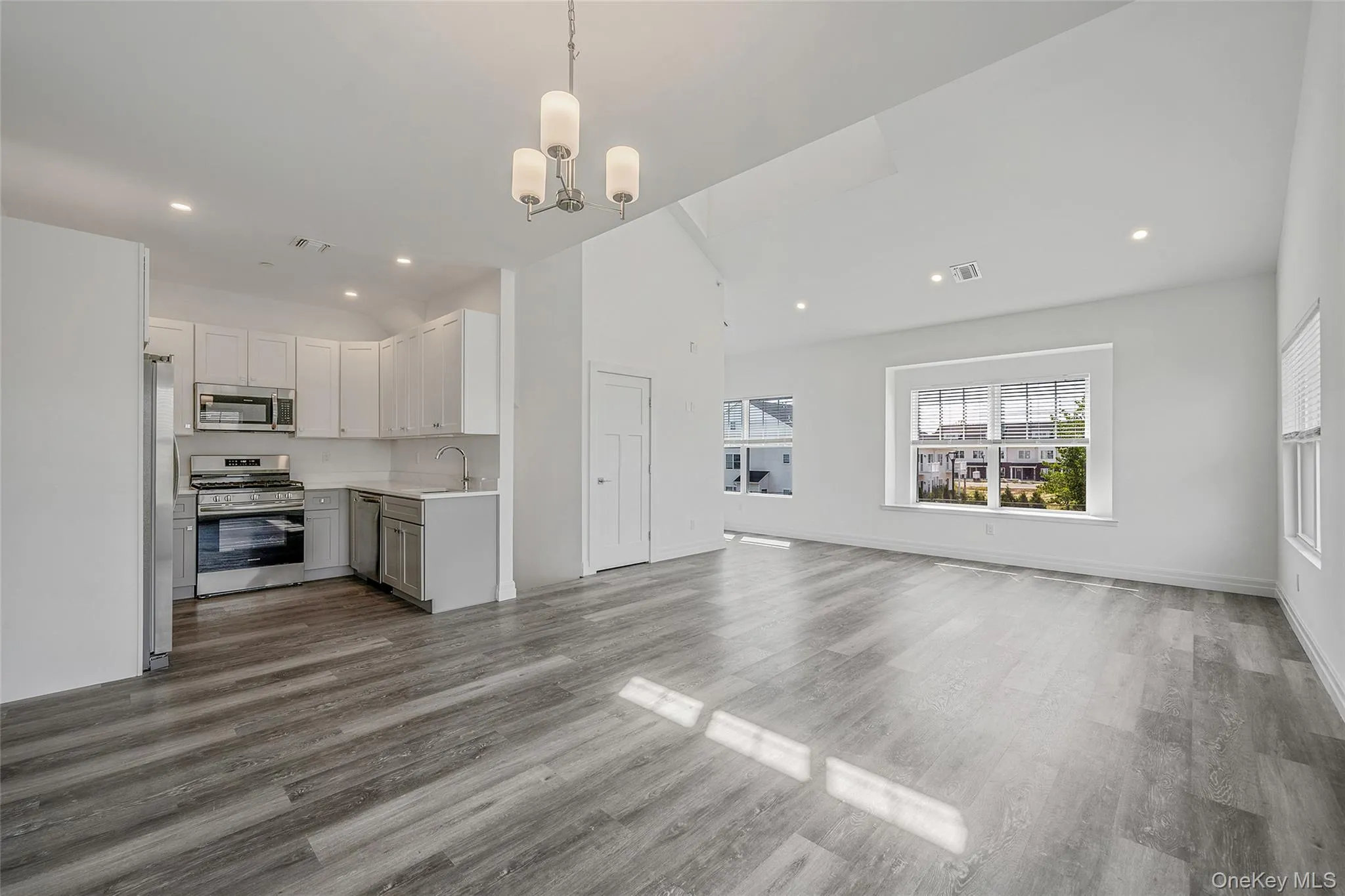 Unfurnished living room featuring a chandelier, vaulted ceiling, wood finished floors, and recessed lighting Unfurnished living room featuring a chandelier, vaulted ceiling, wood finished floors, and recessed lighting