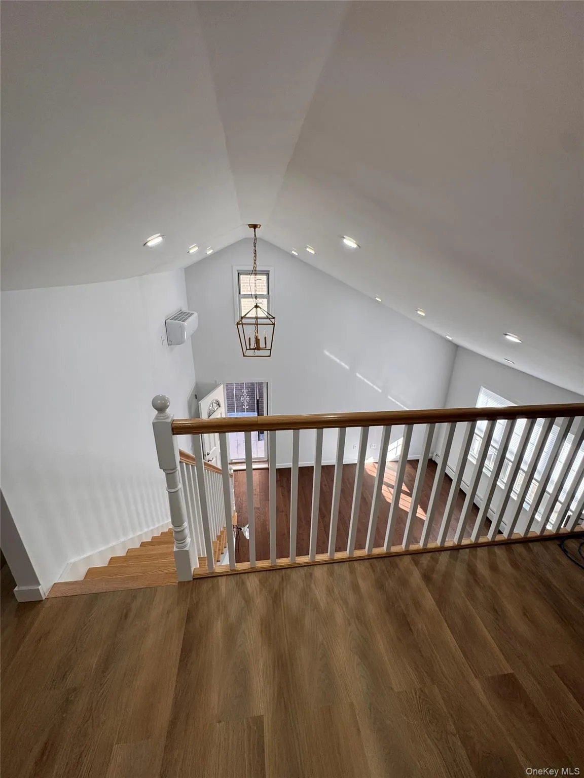 Stairway featuring lofted ceiling, wood finished floors, a chandelier, and recessed lighting Stairway featuring lofted ceiling, wood finished floors, a chandelier, and recessed lighting