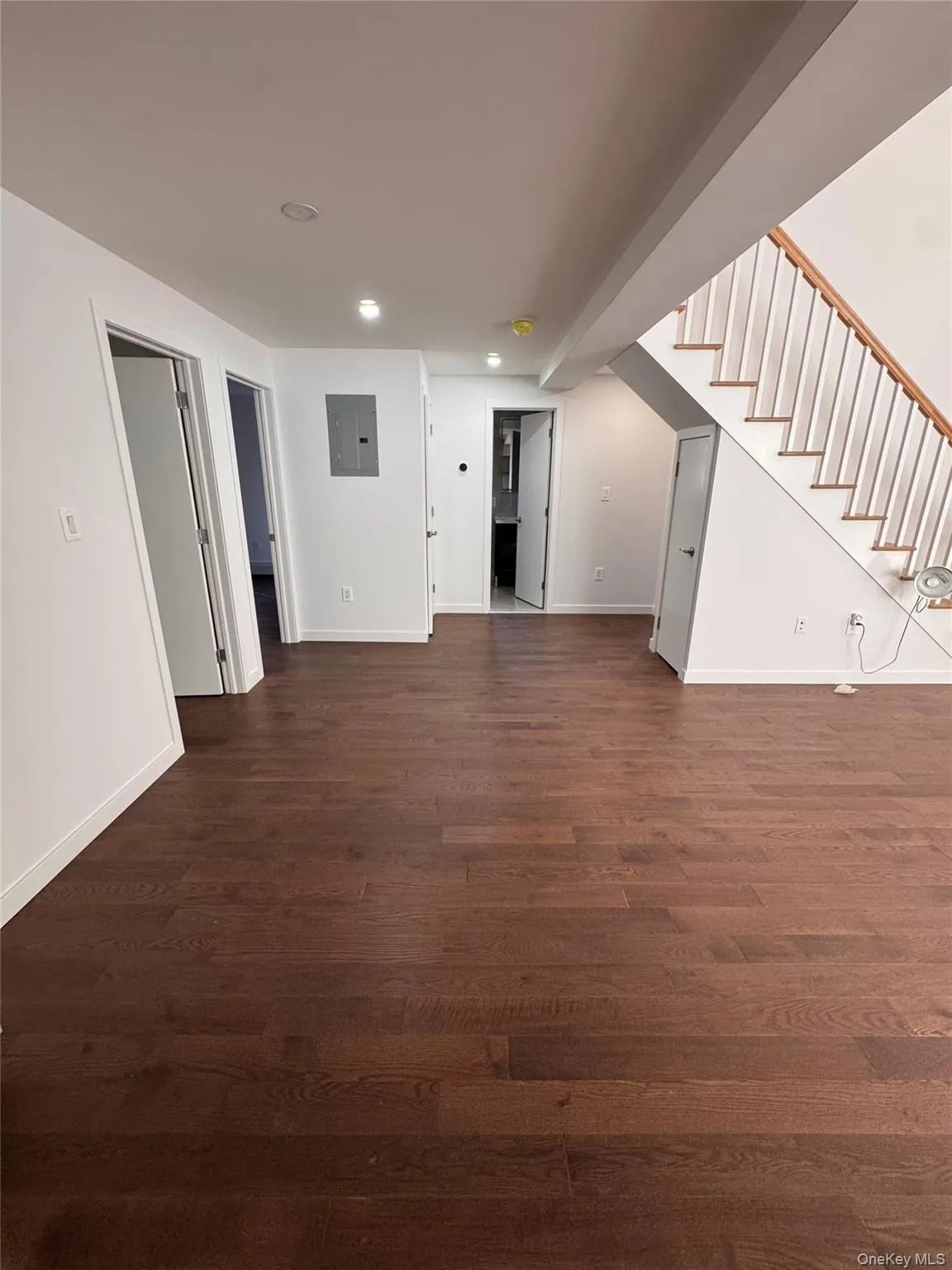 Unfurnished living room with stairway, dark wood-style flooring, recessed lighting, and electric panel Unfurnished living room with stairway, dark wood-style flooring, recessed lighting, and electric panel