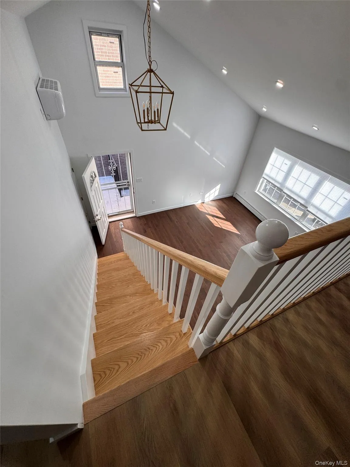 Stairway with wood finished floors, high vaulted ceiling, a chandelier, baseboard heating, and recessed lighting Stairway with wood finished floors, high vaulted ceiling, a chandelier, baseboard heating, and recessed lighting
