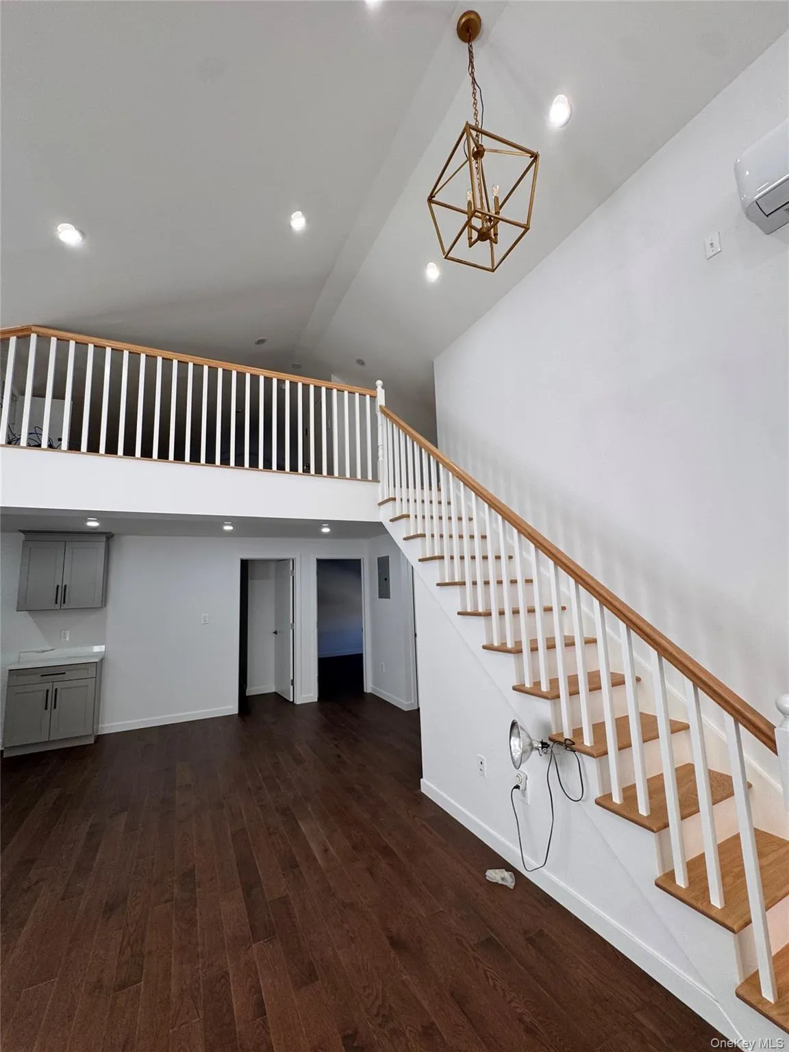 Stairs with wood finished floors, high vaulted ceiling, recessed lighting, a wall mounted air conditioner, and a chandelier Stairs with wood finished floors, high vaulted ceiling, recessed lighting, a wall mounted air conditioner, and a chandelier