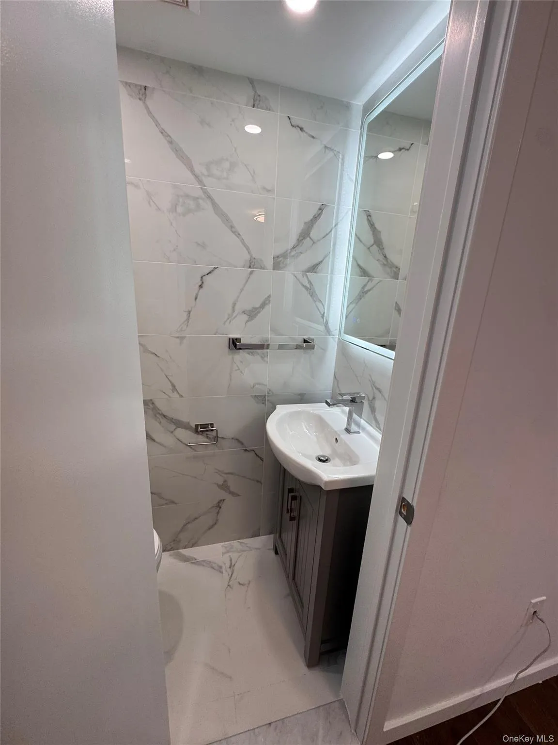 Full bathroom with vanity, light marble finish flooring, tile walls, and a marble finish shower Full bathroom with vanity, light marble finish flooring, tile walls, and a marble finish shower