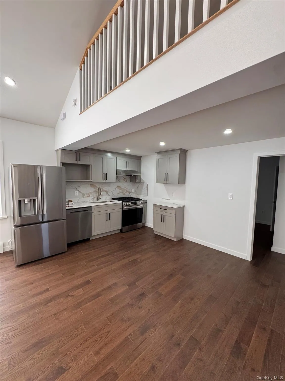 Kitchen with appliances with stainless steel finishes, gray cabinets, recessed lighting, tasteful backsplash, and dark wood-style flooring Kitchen with appliances with stainless steel finishes, gray cabinets, recessed lighting, tasteful backsplash, and dark wood-style flooring