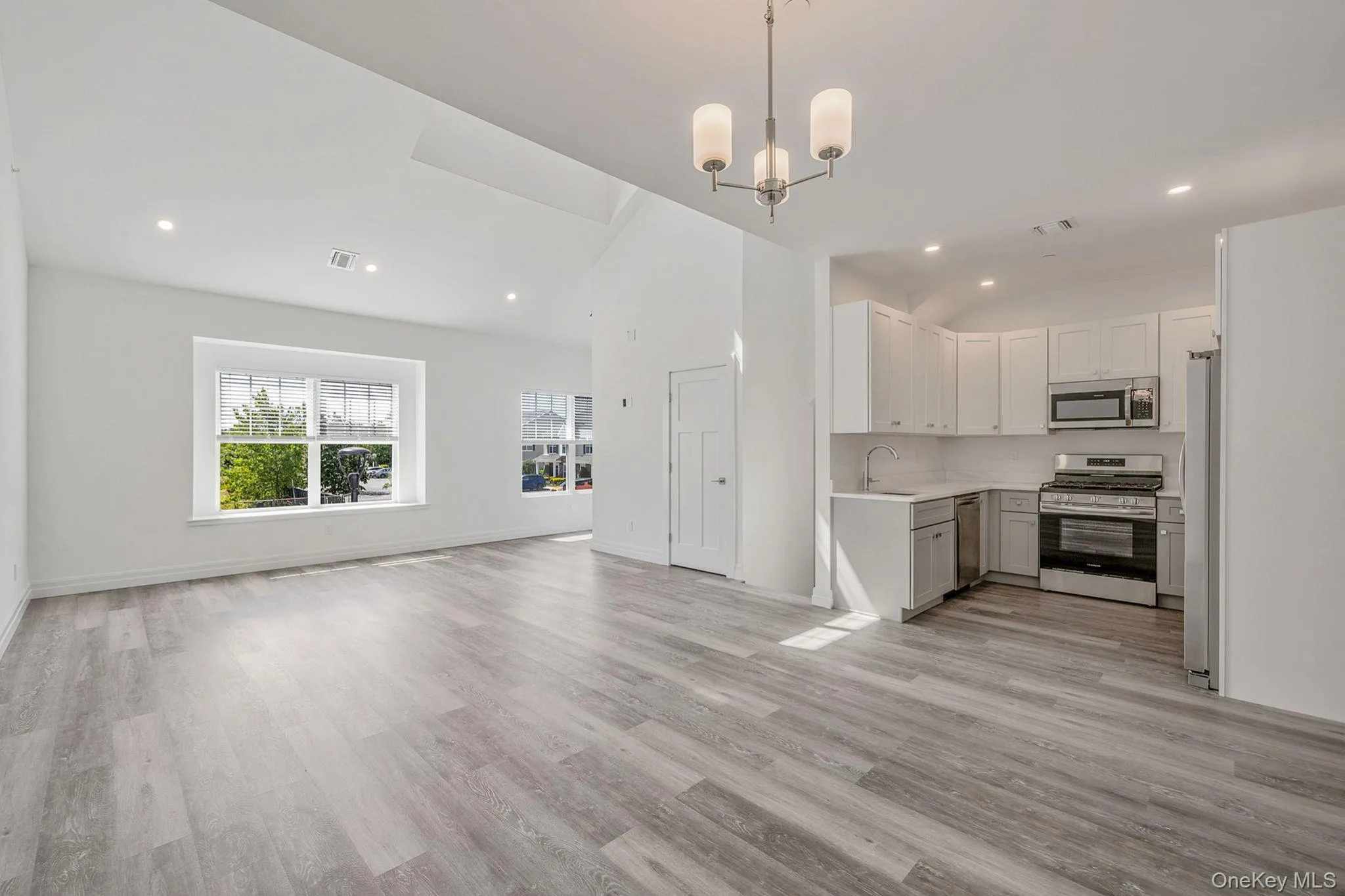 Unfurnished living room featuring recessed lighting, light wood-type flooring, a chandelier, and vaulted ceiling Unfurnished living room featuring recessed lighting, light wood-type flooring, a chandelier, and vaulted ceiling