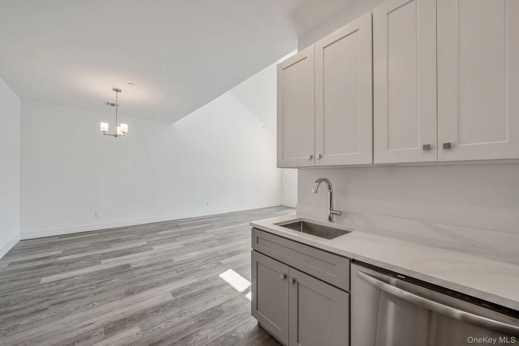 Kitchen with dishwasher, light wood-type flooring, light stone counters, decorative light fixtures, and a chandelier Kitchen with dishwasher, light wood-type flooring, light stone counters, decorative light fixtures, and a chandelier