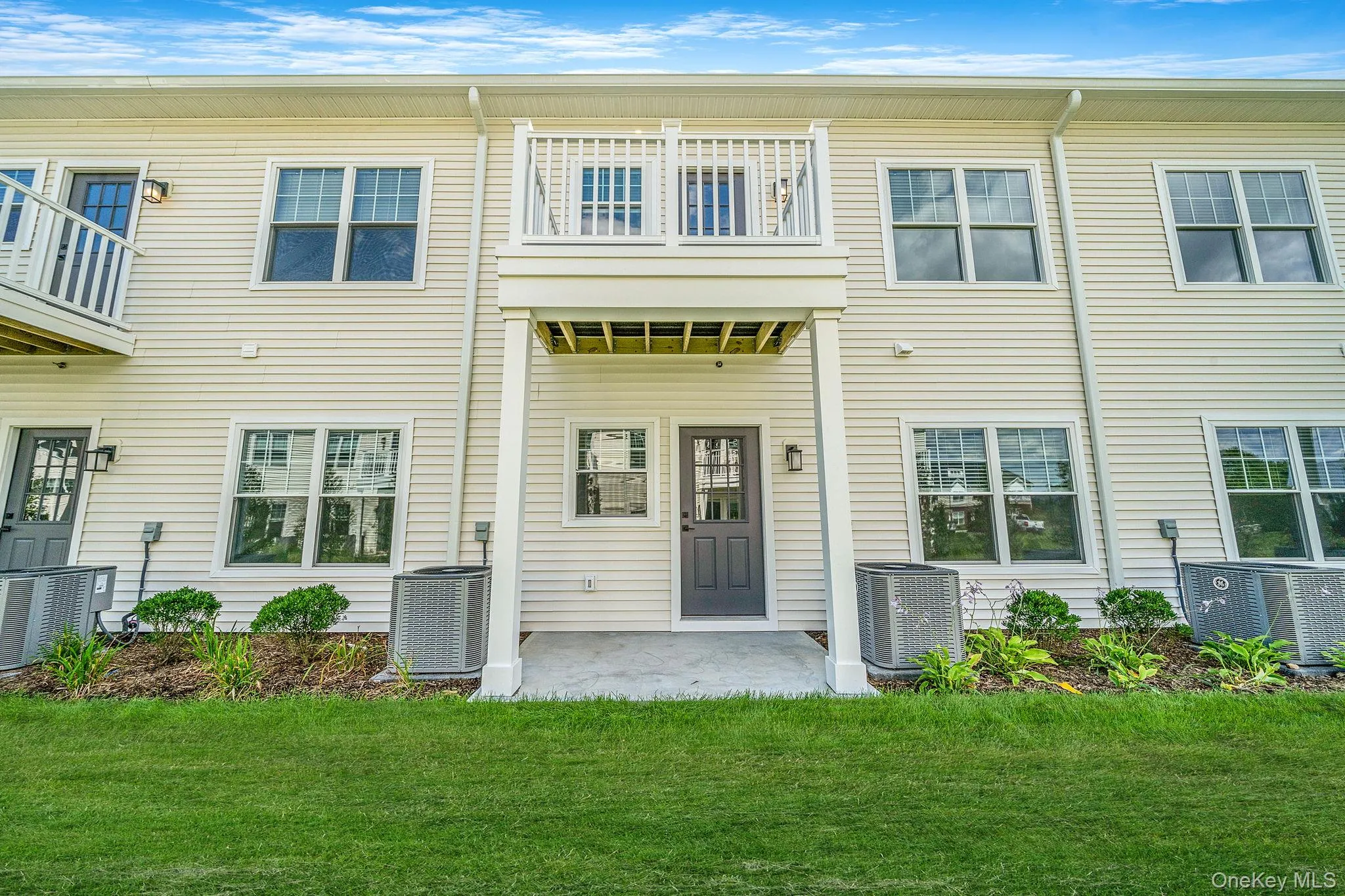 Rear view of property featuring a balcony, a patio area, and a lawn Rear view of property featuring a balcony, a patio area, and a lawn