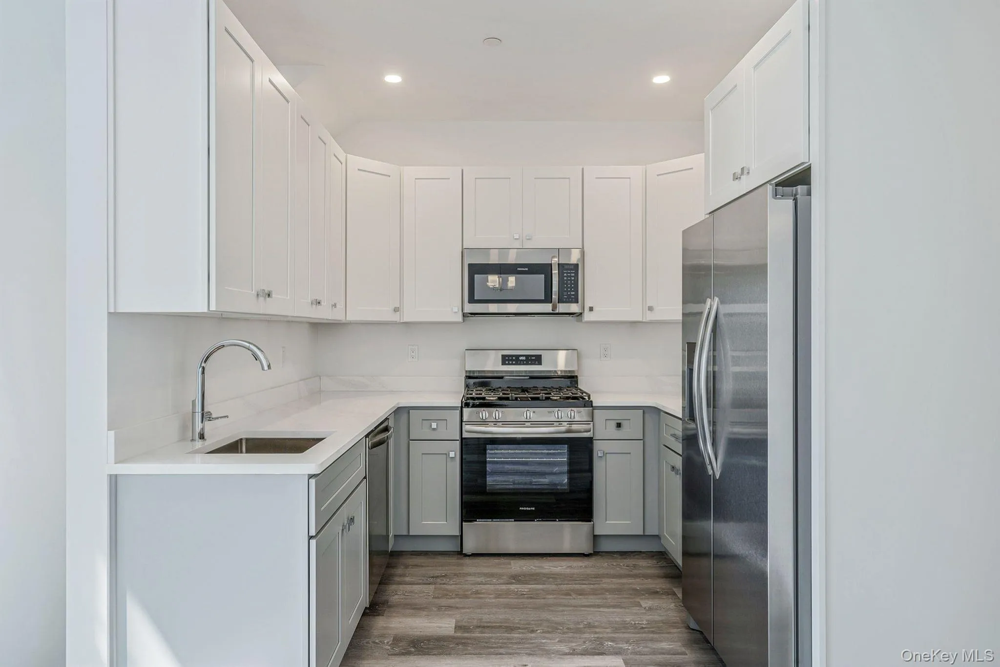 Kitchen with gray cabinetry, stainless steel appliances, light wood-type flooring, white cabinetry, and light stone counters Kitchen with gray cabinetry, stainless steel appliances, light wood-type flooring, white cabinetry, and light stone counters
