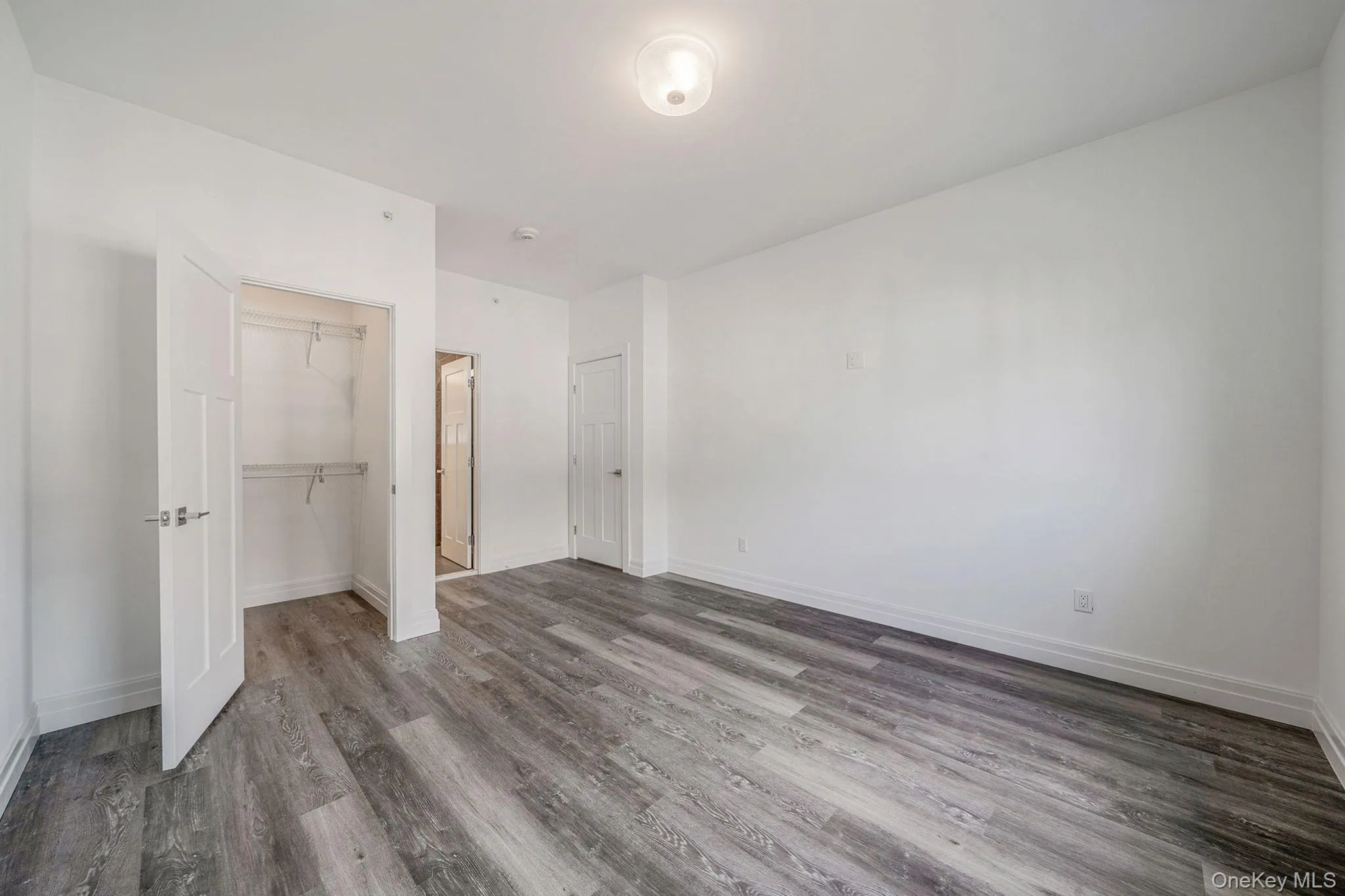 Unfurnished bedroom featuring wood finished floors and a closet Unfurnished bedroom featuring wood finished floors and a closet