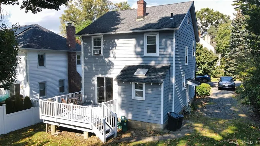 Back of house with a chimney, a wooden deck, and roof with shingles Back of house with a chimney, a wooden deck, and roof with shingles