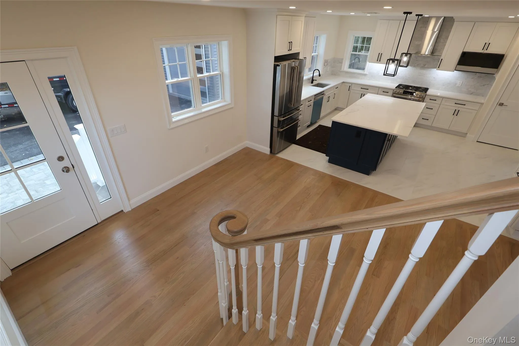 Kitchen featuring white cabinetry, stainless steel appliances, a kitchen island, decorative backsplash, and light wood-type flooring Kitchen featuring white cabinetry, stainless steel appliances, a kitchen island, decorative backsplash, and light wood-type flooring