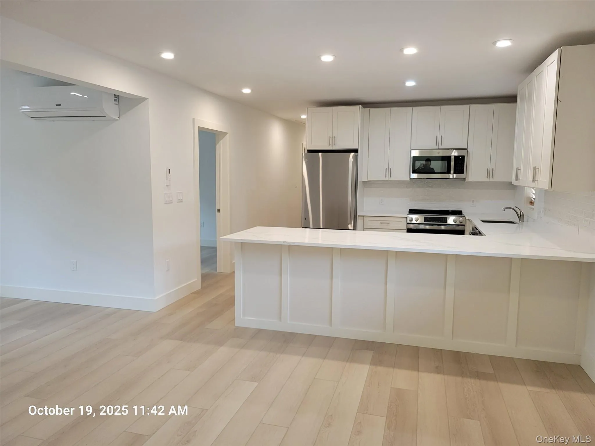 Kitchen with recessed lighting, appliances with stainless steel finishes, light wood-type flooring, a peninsula, and white cabinetry Kitchen with recessed lighting, appliances with stainless steel finishes, light wood-type flooring, a peninsula, and white cabinetry