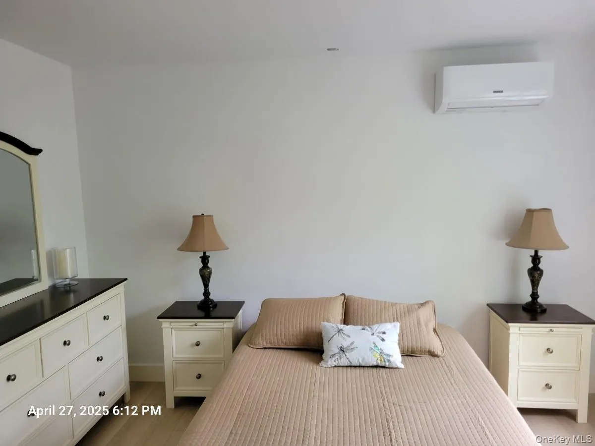 Bedroom featuring a wall mounted AC and wood finished floors Bedroom featuring a wall mounted AC and wood finished floors