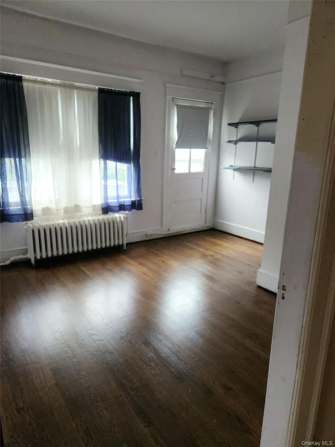 Unfurnished room with radiator heating unit and wood finished floors Unfurnished room with radiator heating unit and wood finished floors