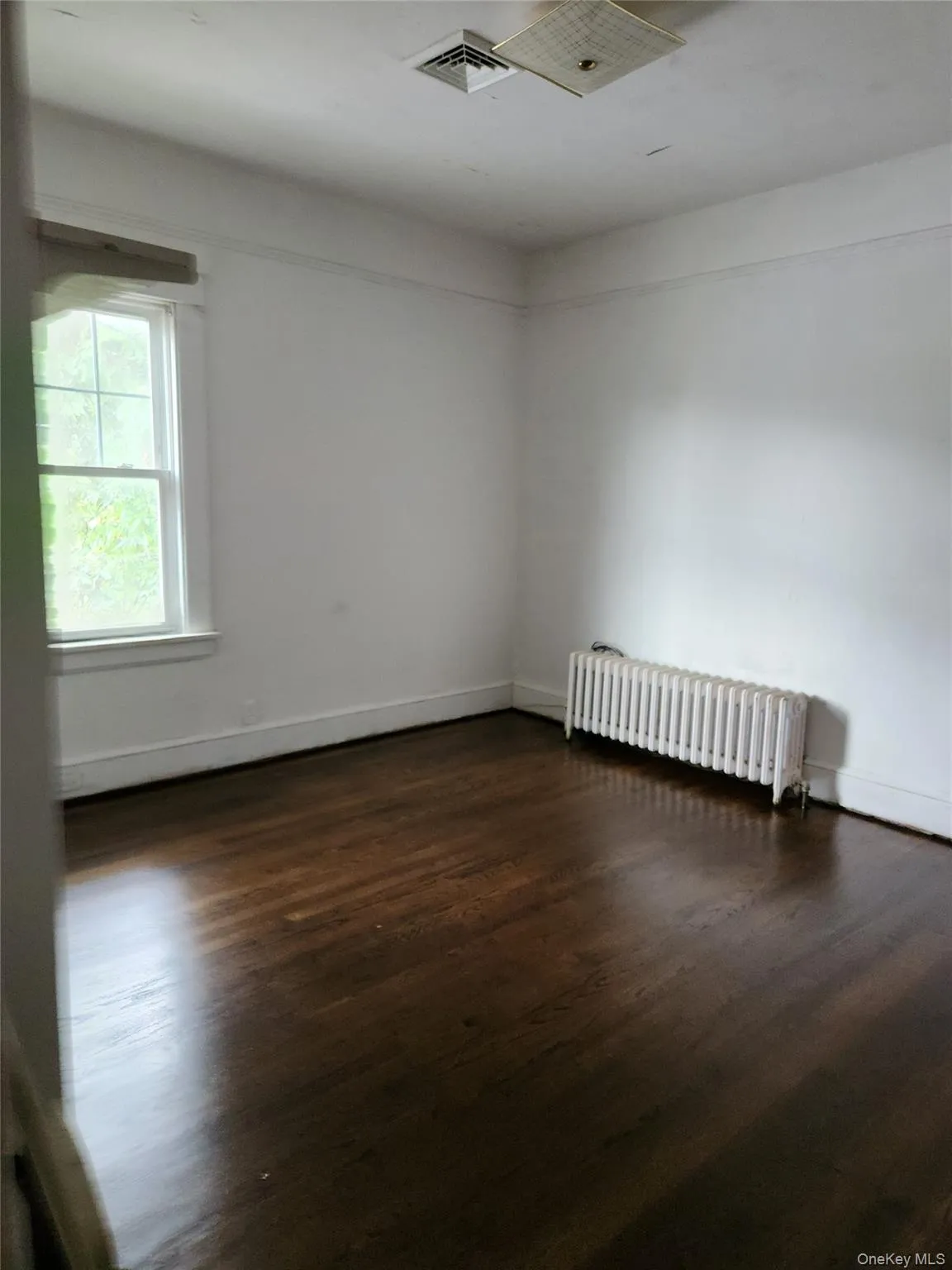 Empty room with radiator and dark wood finished floors Empty room with radiator and dark wood finished floors