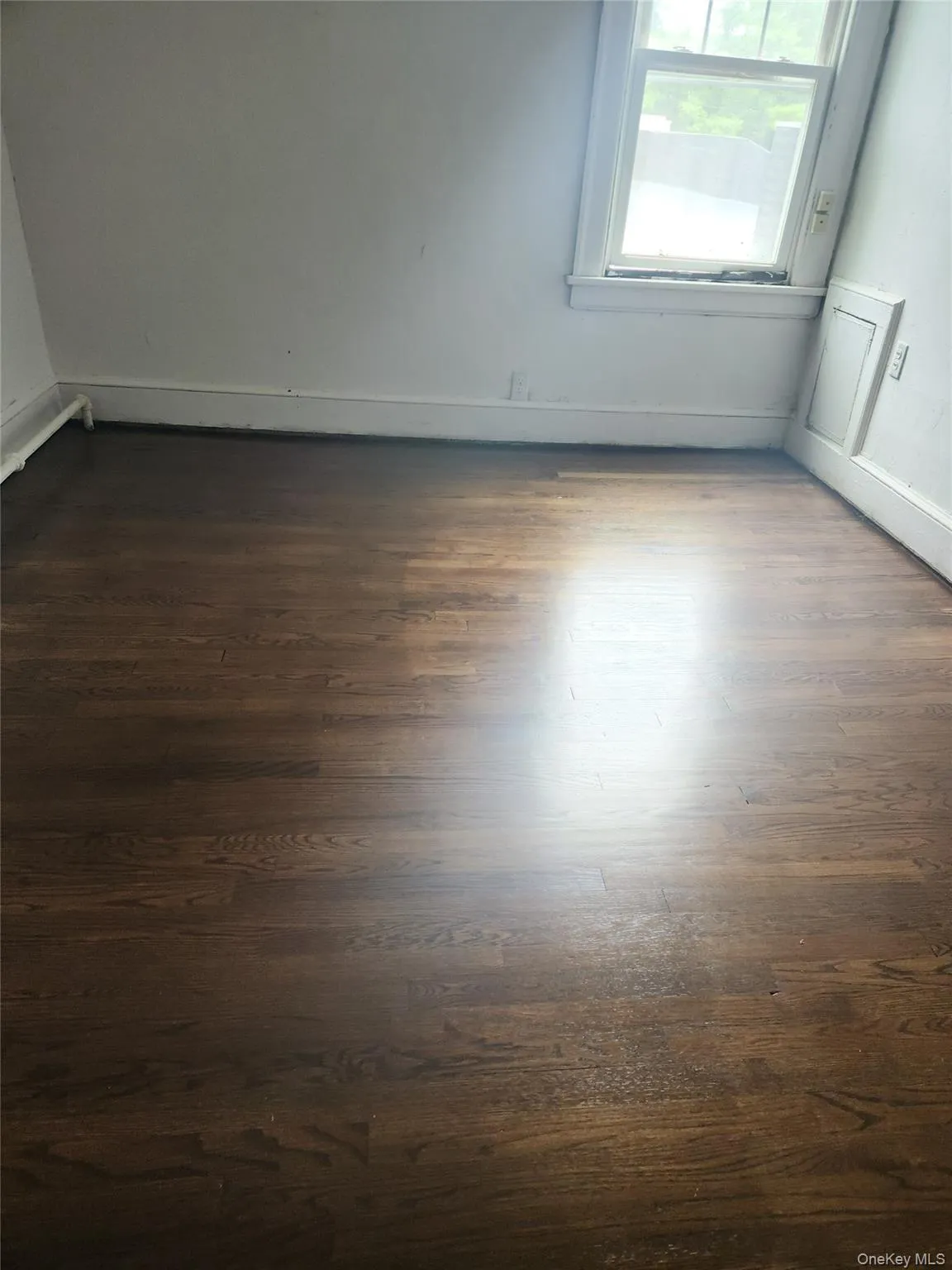 Empty room featuring dark wood-style floors and baseboards Empty room featuring dark wood-style floors and baseboards