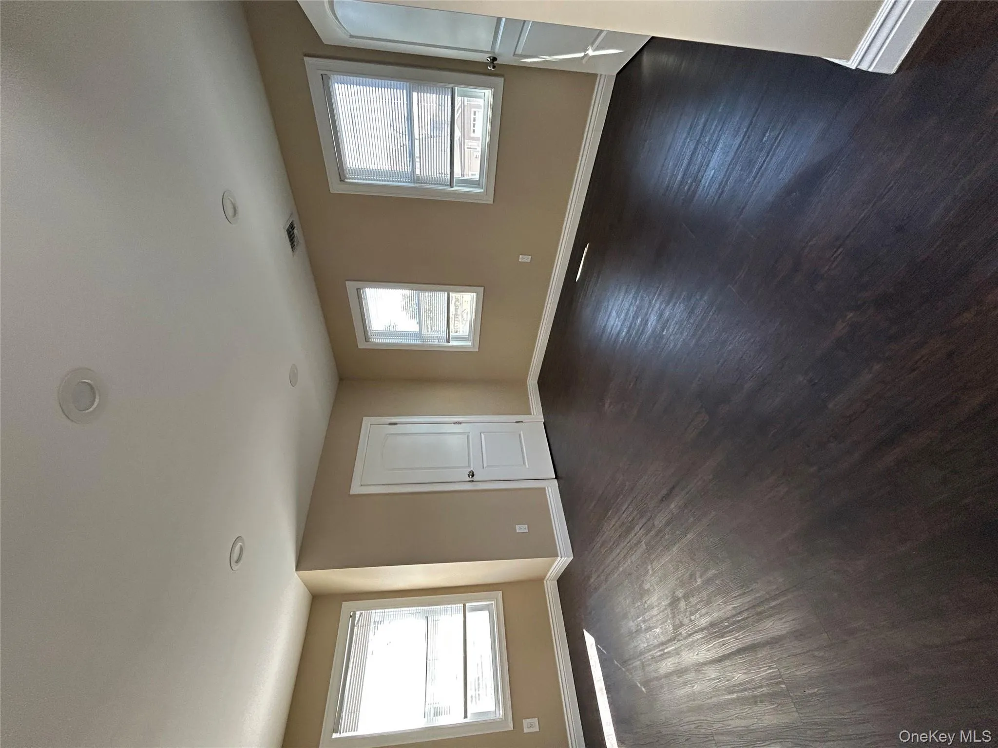 Empty room with dark wood-style flooring and healthy amount of natural light Empty room with dark wood-style flooring and healthy amount of natural light