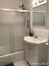 Bathroom featuring vanity, combined bath / shower with glass door, and dark tile patterned flooring Bathroom featuring vanity, combined bath / shower with glass door, and dark tile patterned flooring