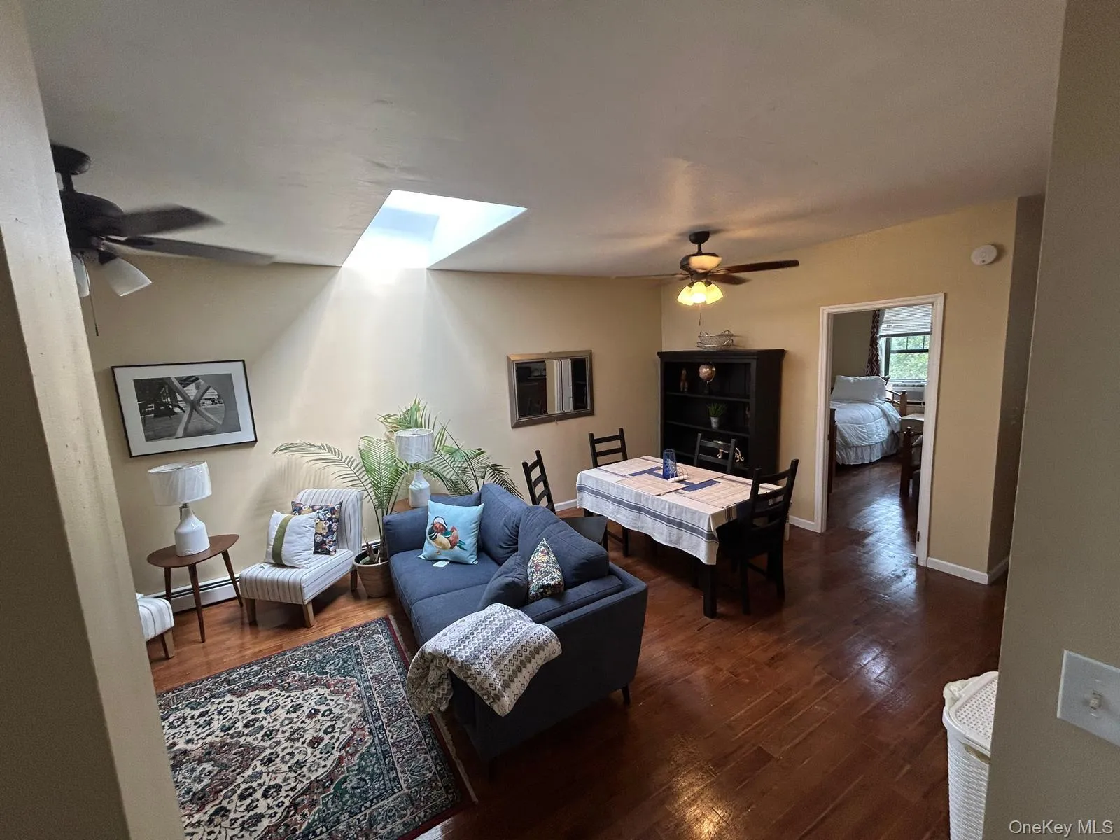 Living area featuring a skylight, a ceiling fan, and wood finished floors Living area featuring a skylight, a ceiling fan, and wood finished floors