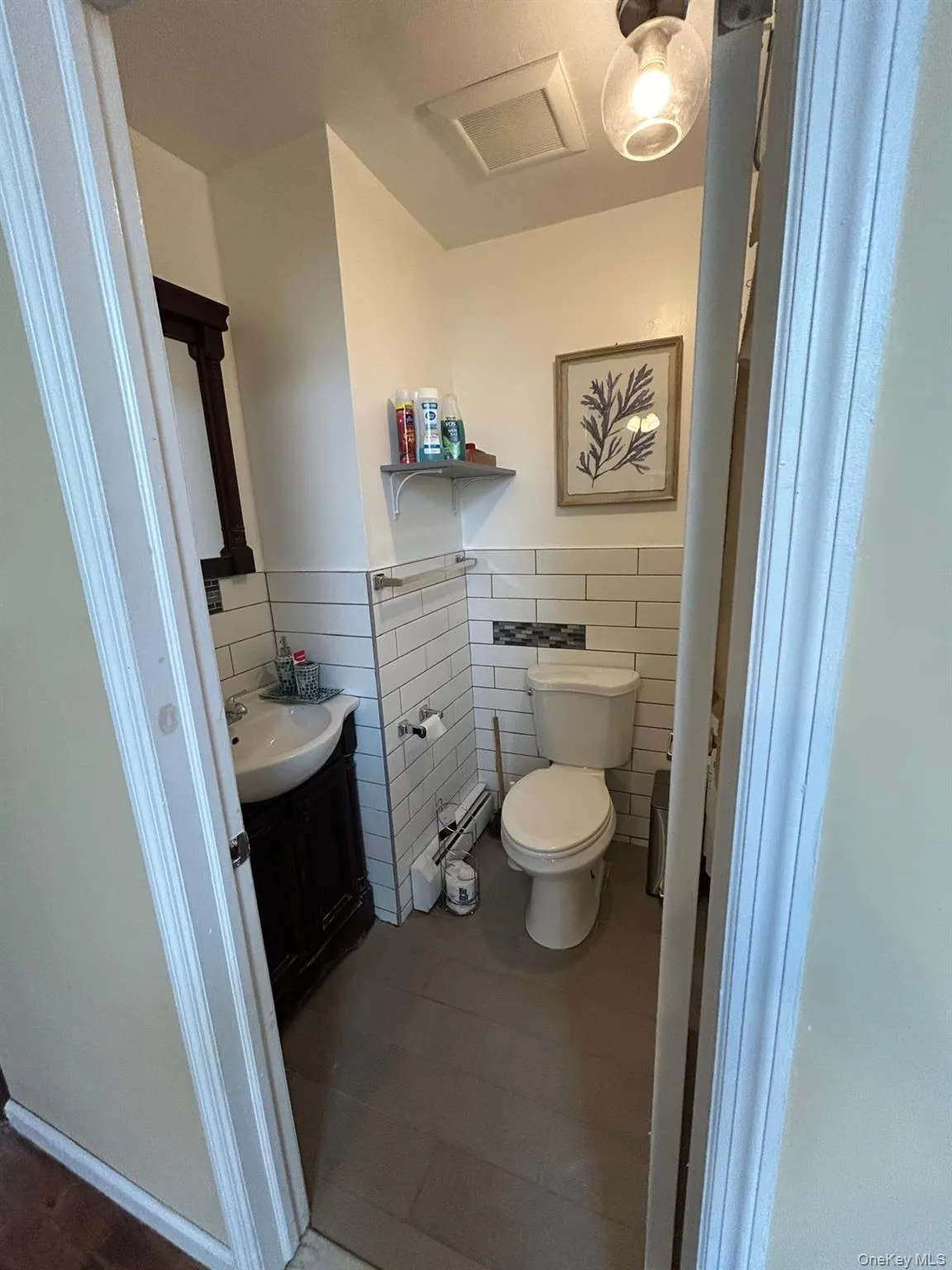 Bathroom featuring vanity, tile walls, a wainscoted wall, dark tile patterned flooring, and a baseboard radiator Bathroom featuring vanity, tile walls, a wainscoted wall, dark tile patterned flooring, and a baseboard radiator