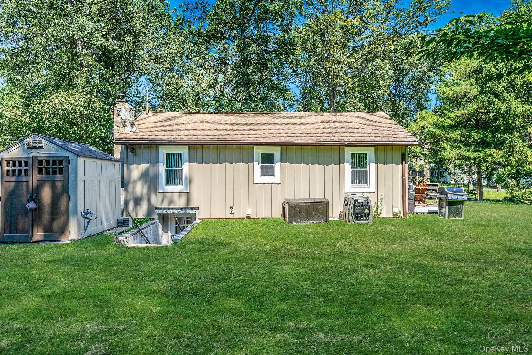 Back of house with a chimney, board and batten siding, a lawn, and a storage unit Back of house with a chimney, board and batten siding, a lawn, and a storage unit