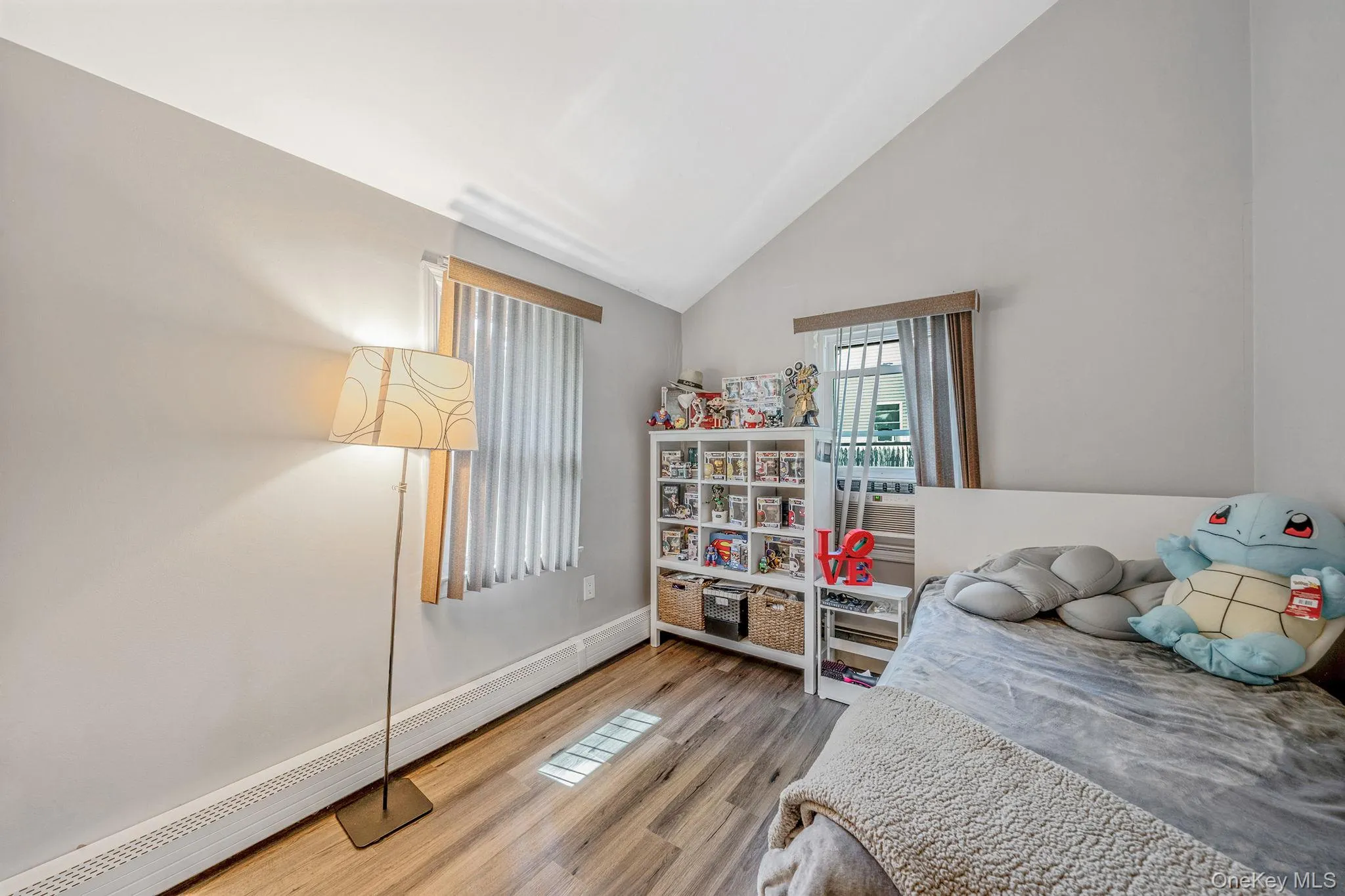 Bedroom featuring baseboard heating, light wood-style floors, and high vaulted ceiling Bedroom featuring baseboard heating, light wood-style floors, and high vaulted ceiling