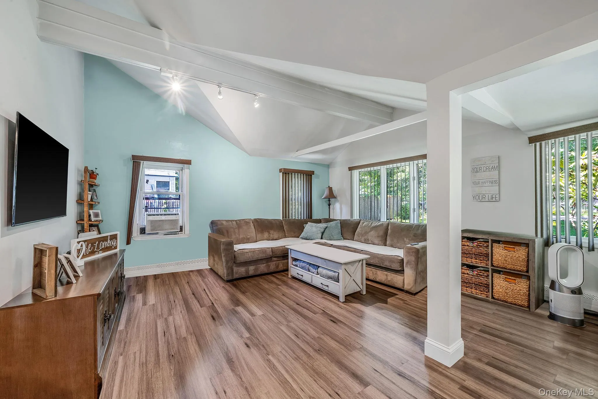 Living room featuring track lighting, healthy amount of natural light, wood finished floors, beamed ceiling, and high vaulted ceiling Living room featuring track lighting, healthy amount of natural light, wood finished floors, beamed ceiling, and high vaulted ceiling