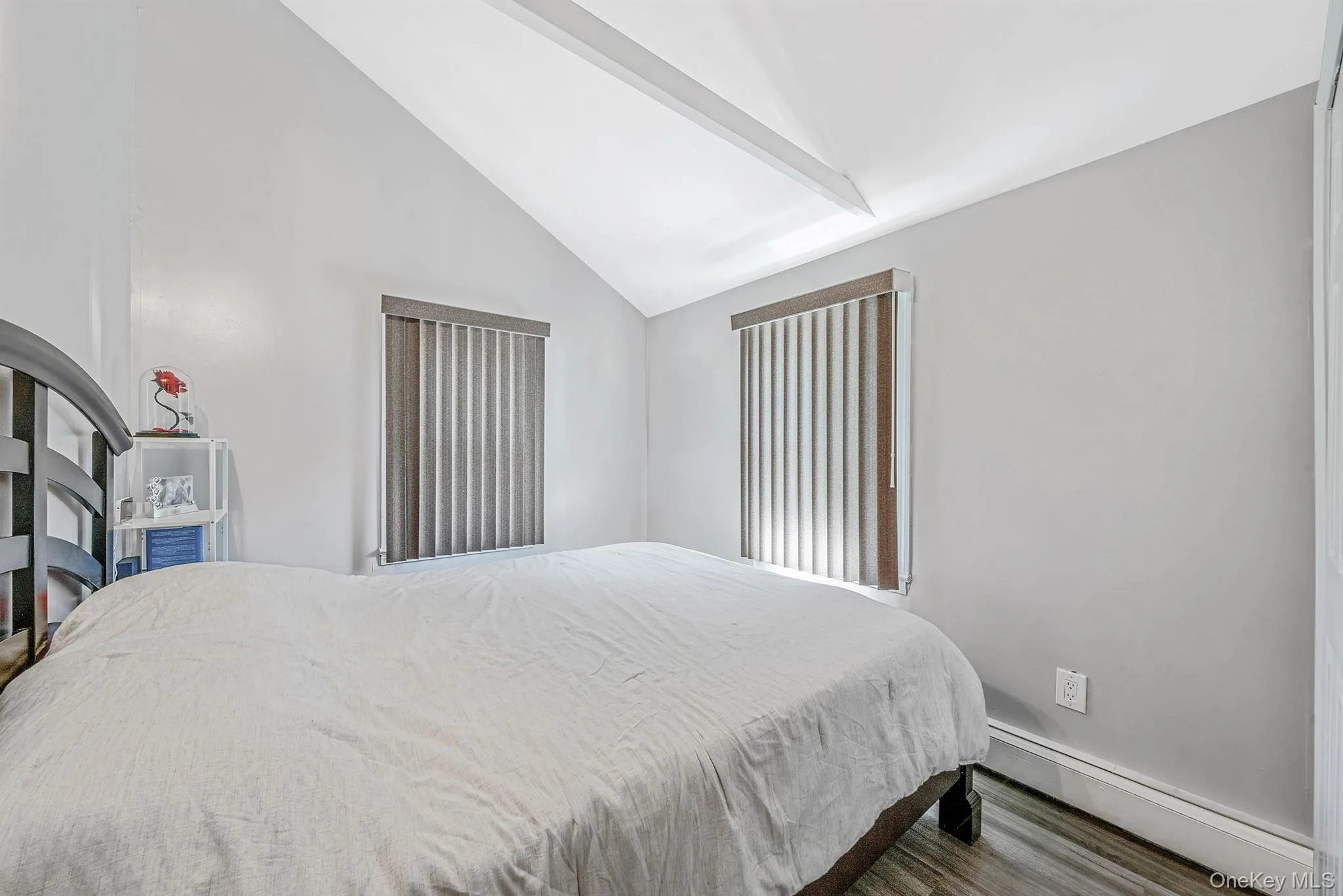 Bedroom with baseboard heating, wood finished floors, high vaulted ceiling, and beam ceiling Bedroom with baseboard heating, wood finished floors, high vaulted ceiling, and beam ceiling