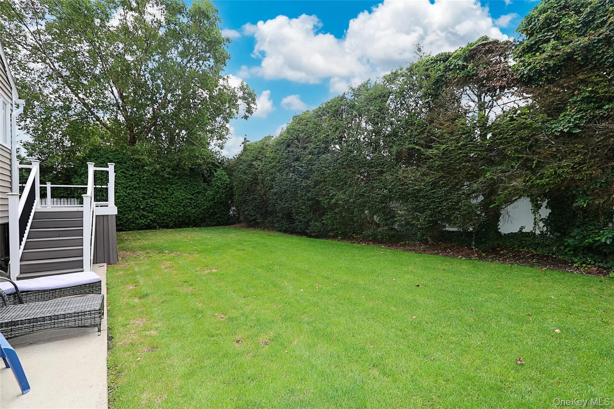 View of green lawn with stairs and a wooden deck View of green lawn with stairs and a wooden deck