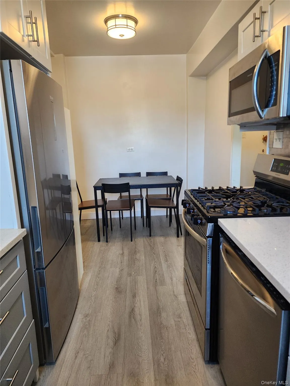 Kitchen featuring stainless steel appliances, light stone countertops, and light wood-type flooring Kitchen featuring stainless steel appliances, light stone countertops, and light wood-type flooring