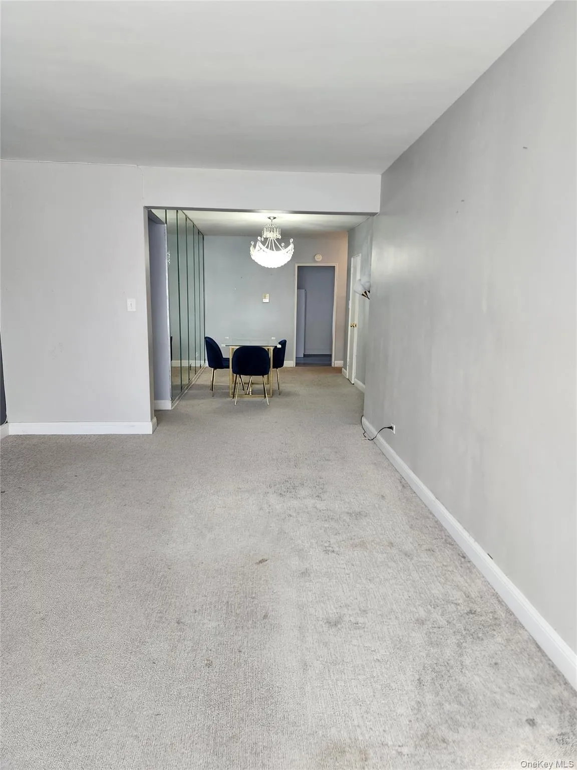 Carpeted empty room featuring a chandelier and baseboards Carpeted empty room featuring a chandelier and baseboards