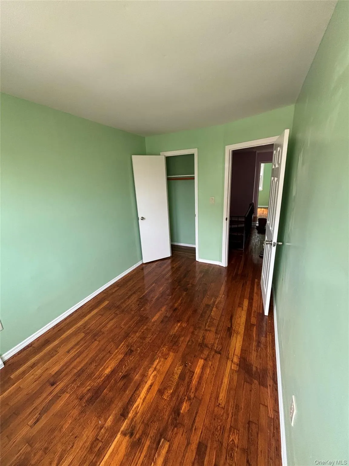 Unfurnished bedroom with dark wood finished floors and a closet Unfurnished bedroom with dark wood finished floors and a closet