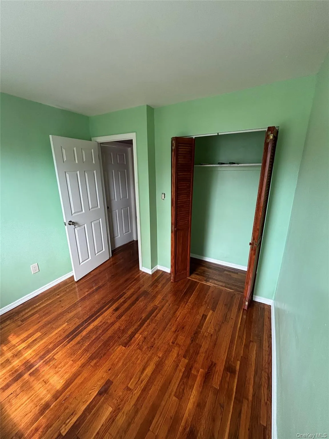 Unfurnished bedroom with dark wood-type flooring and a closet Unfurnished bedroom with dark wood-type flooring and a closet
