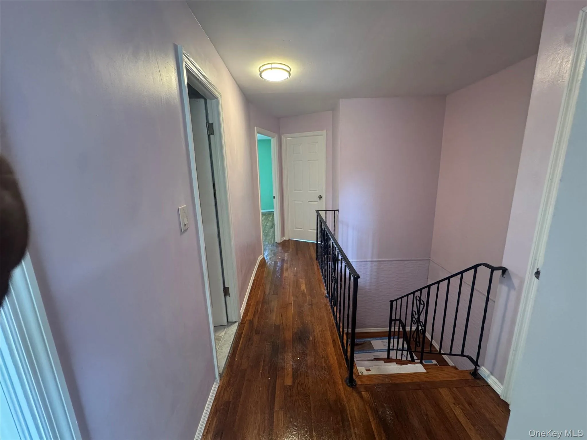 Hallway featuring an upstairs landing and dark wood-style flooring Hallway featuring an upstairs landing and dark wood-style flooring