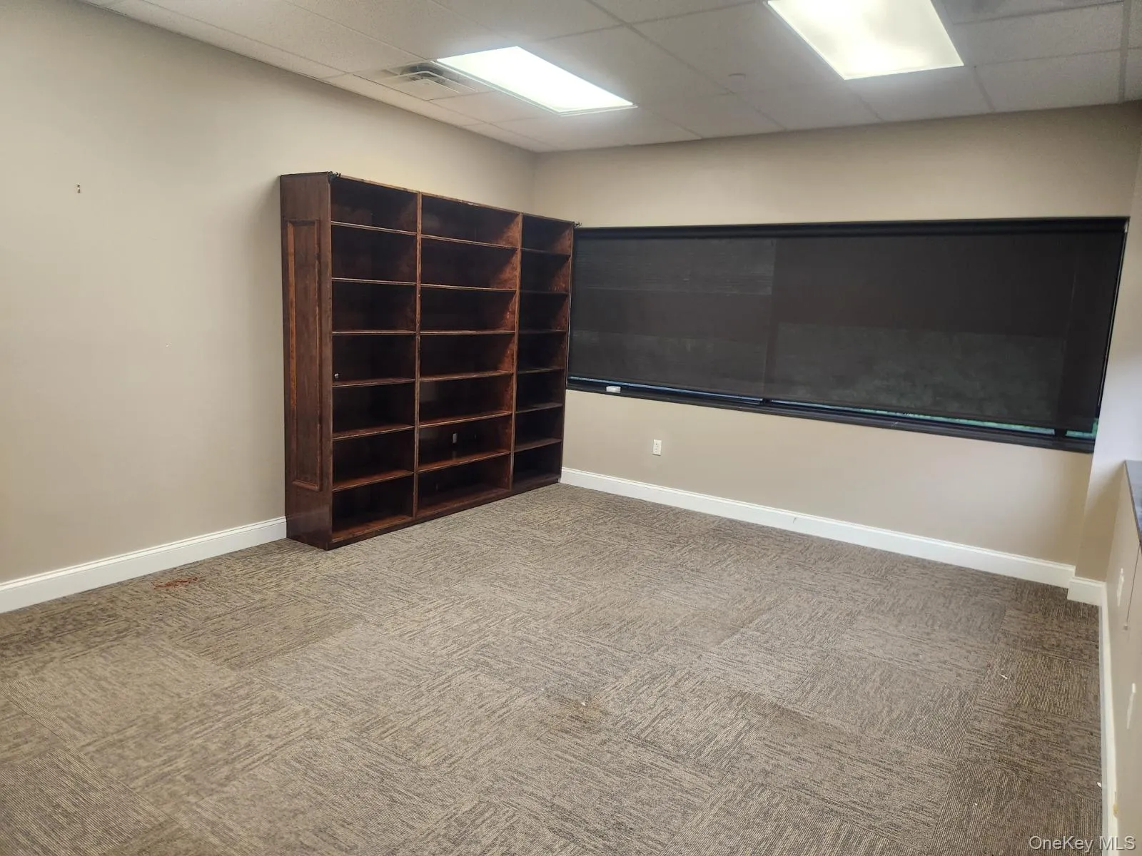 Empty room featuring a drop ceiling and carpet flooring Empty room featuring a drop ceiling and carpet flooring