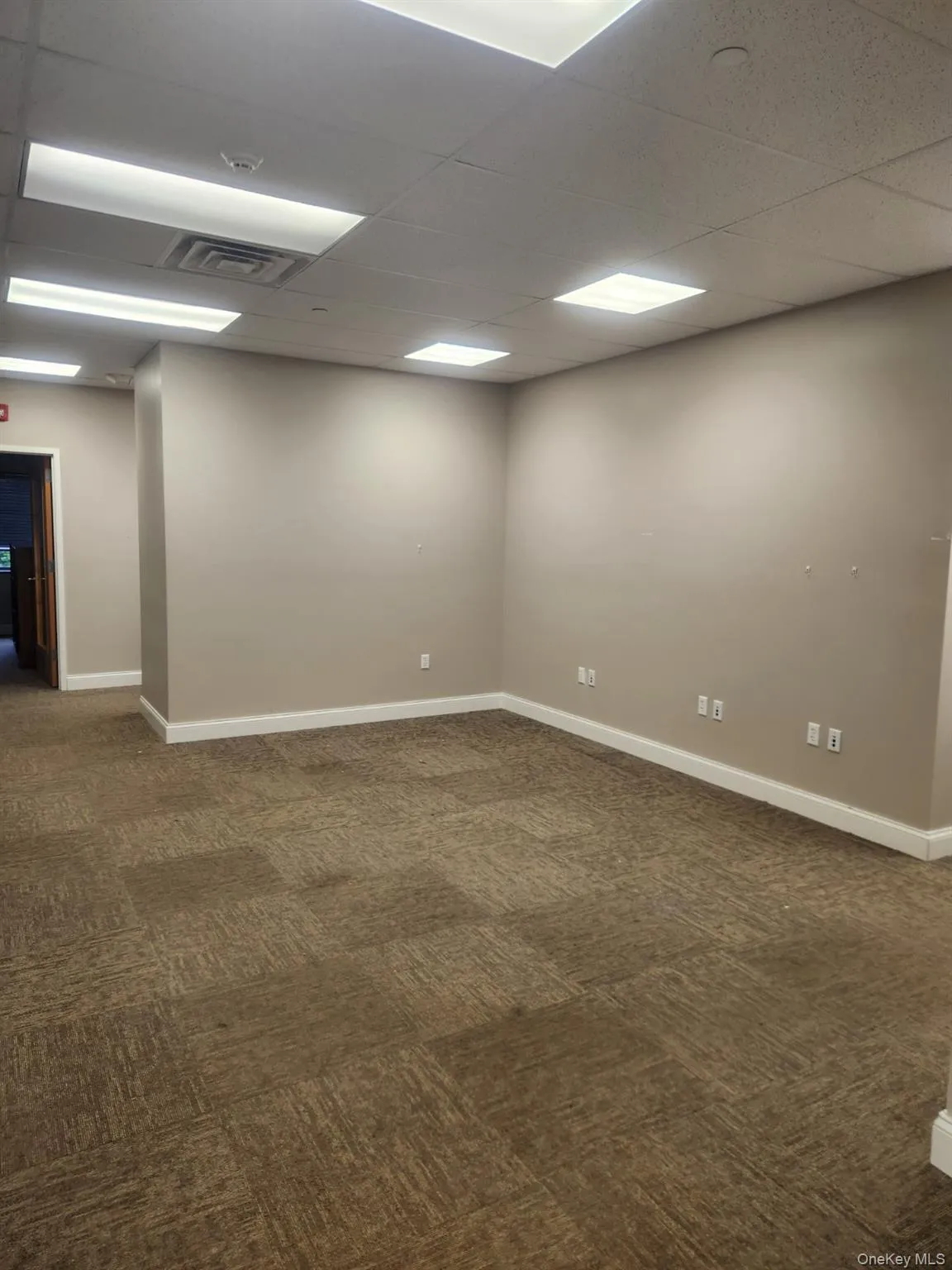 Empty room with dark colored carpet and a drop ceiling Empty room with dark colored carpet and a drop ceiling