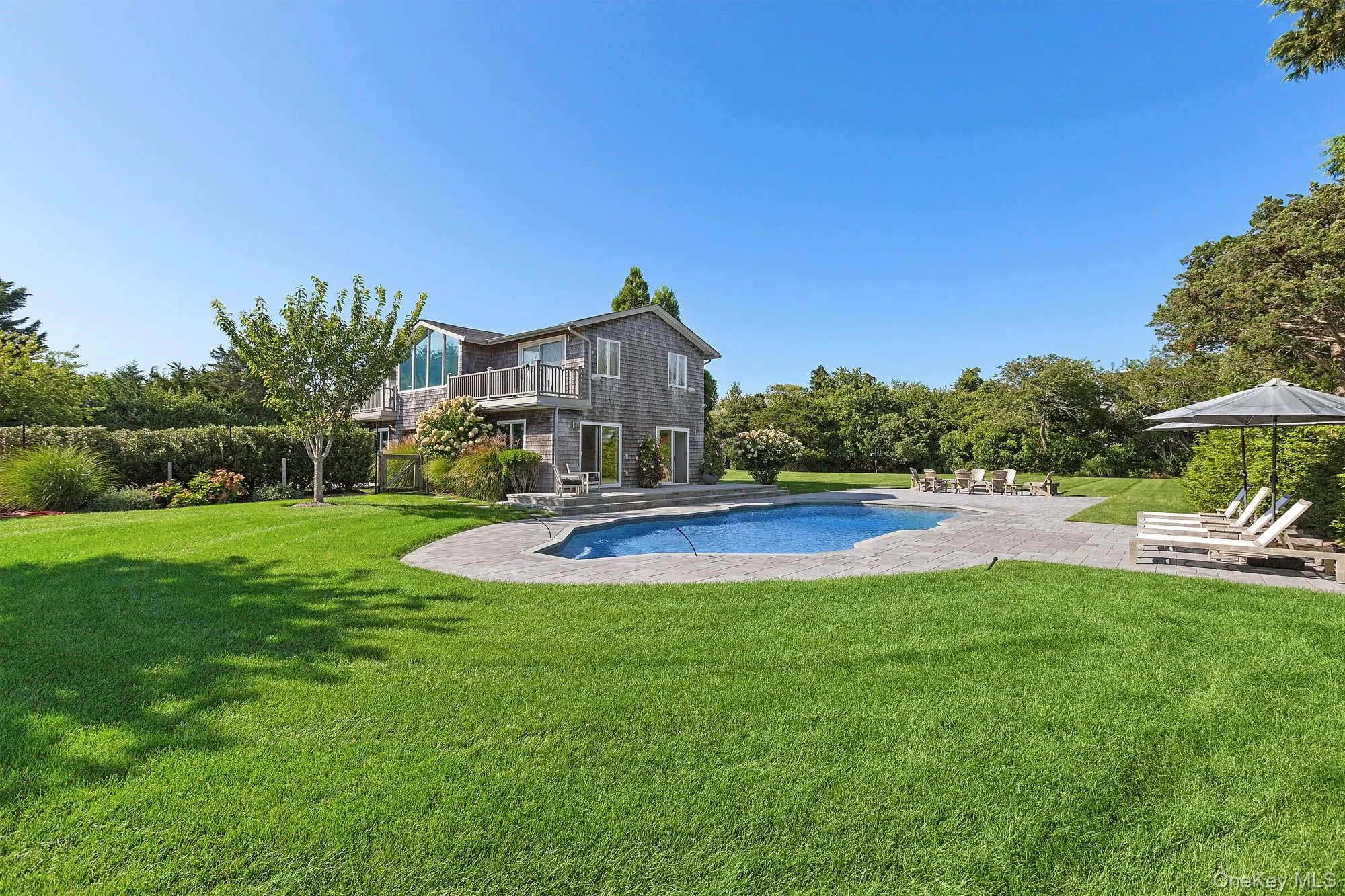 Outdoor pool featuring a patio, a yard, a balcony, and view of wooded area Outdoor pool featuring a patio, a yard, a balcony, and view of wooded area