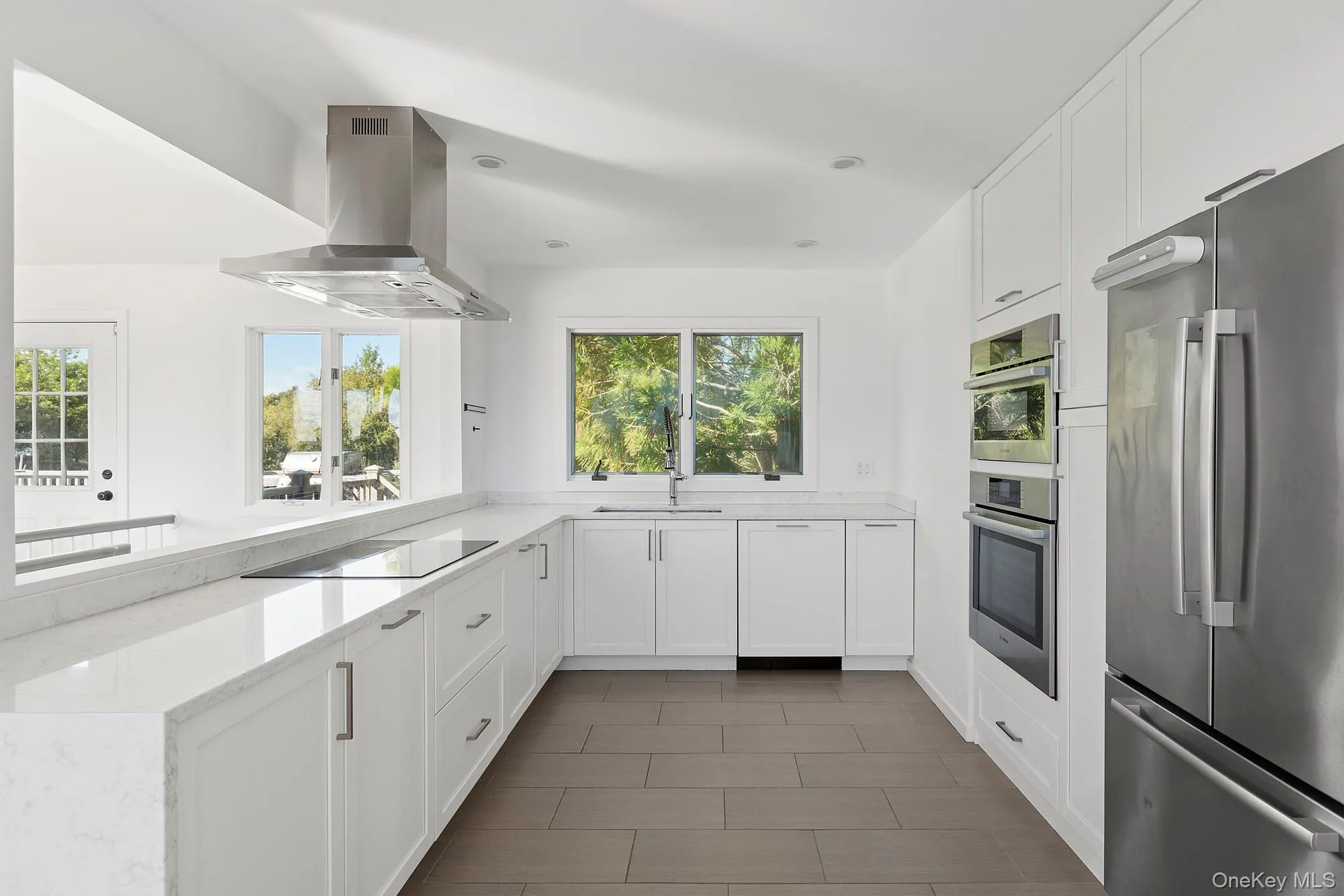 Kitchen featuring white cabinetry, stainless steel appliances, healthy amount of natural light, light stone counters, and recessed lighting Kitchen featuring white cabinetry, stainless steel appliances, healthy amount of natural light, light stone counters, and recessed lighting