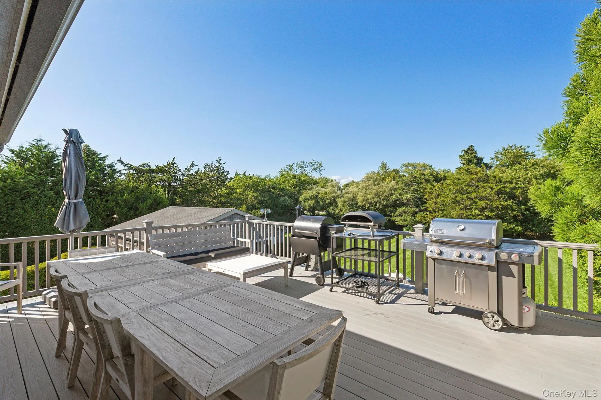 Wooden deck with outdoor dining area, grilling area, and view of scattered trees Wooden deck with outdoor dining area, grilling area, and view of scattered trees