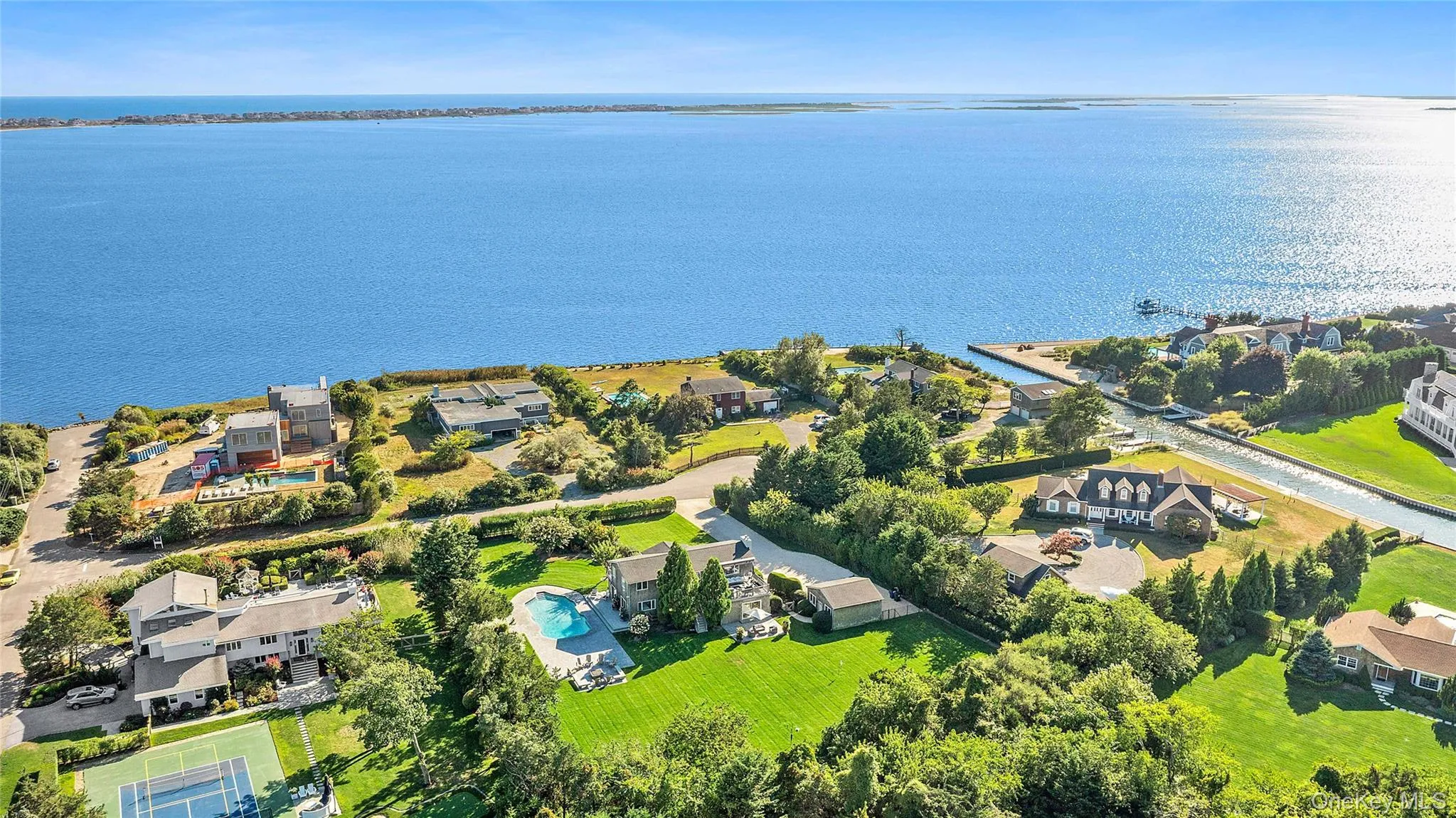 Aerial view of residential area featuring a pool and a nearby body of water Aerial view of residential area featuring a pool and a nearby body of water