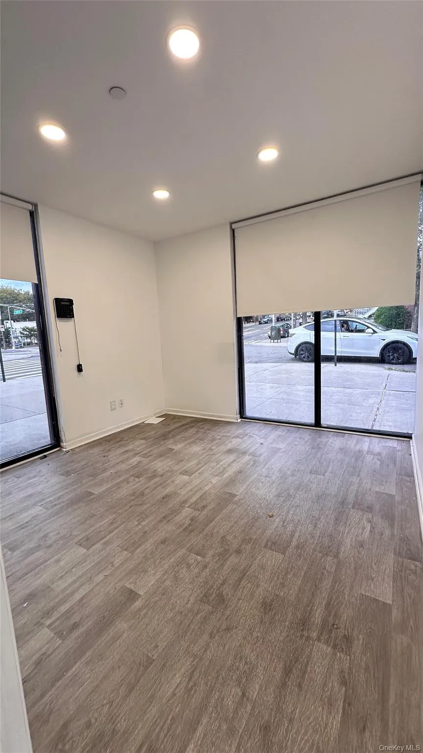 Empty room with recessed lighting, light wood-style floors, and a wall of windows Empty room with recessed lighting, light wood-style floors, and a wall of windows