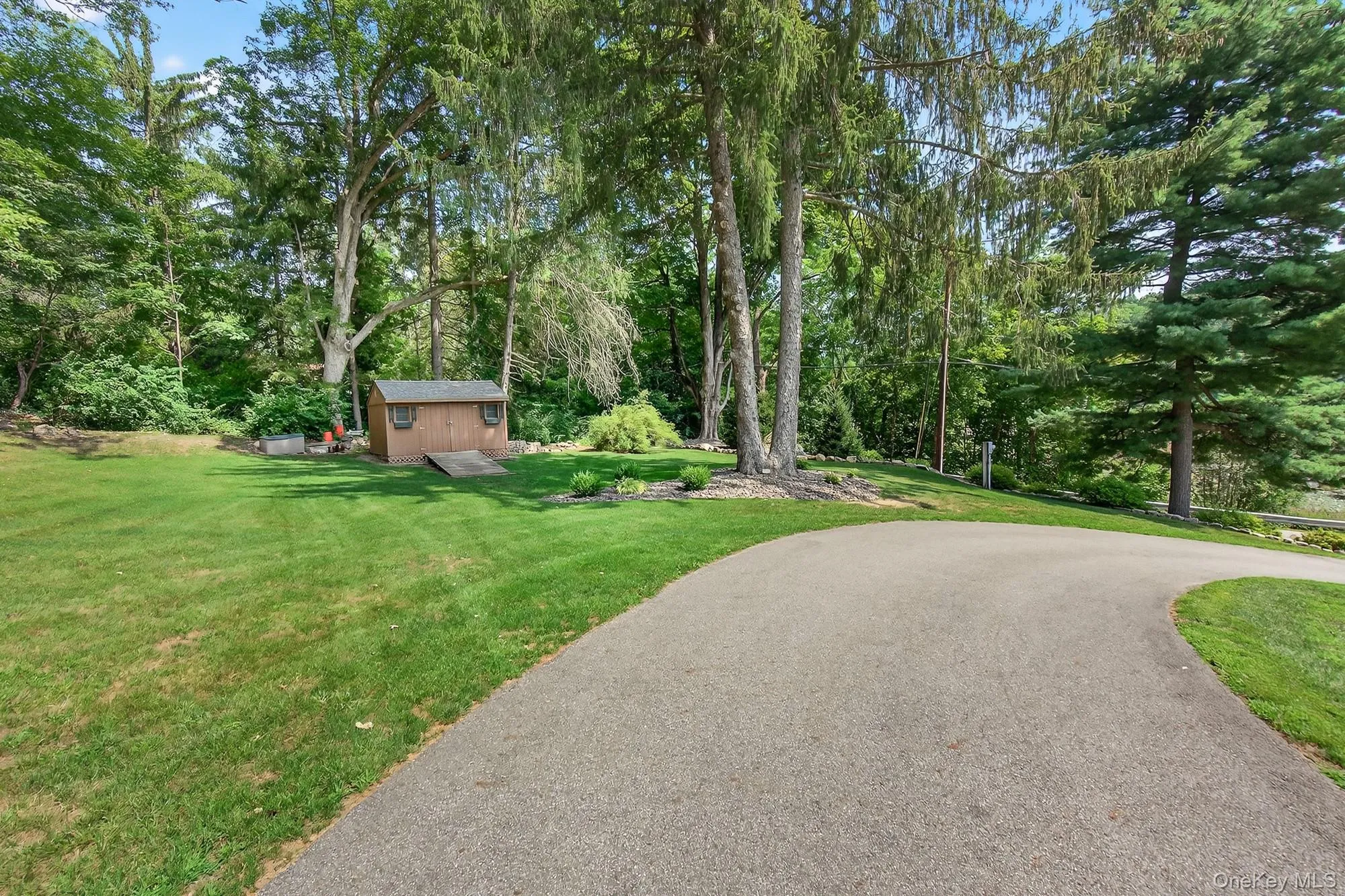 Side yard entrance with a lawn, view of wooded area, and an outbuilding Side yard entrance with a lawn, view of wooded area, and an outbuilding