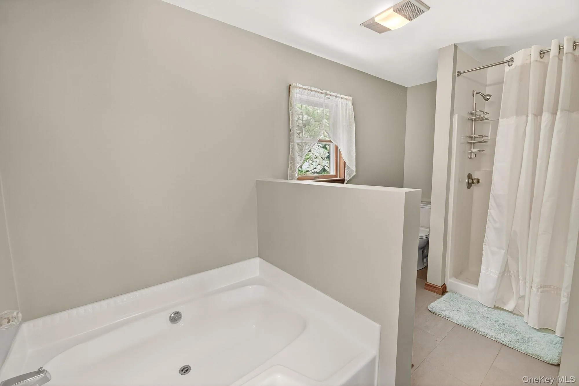 Bathroom with light tile patterned flooring, a stall shower, and a garden tub Bathroom with light tile patterned flooring, a stall shower, and a garden tub